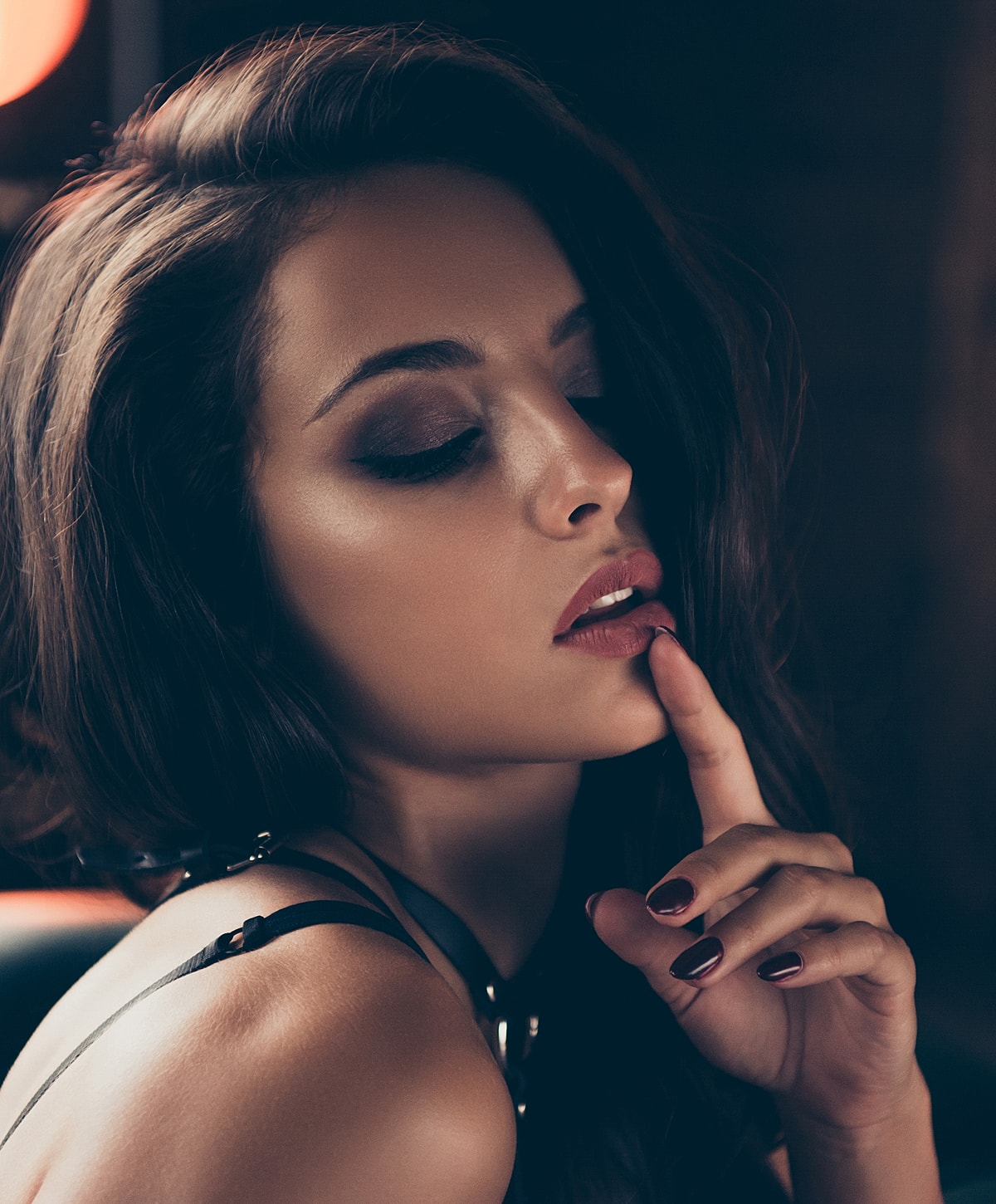 Woman with finger to lips, soft lighting.