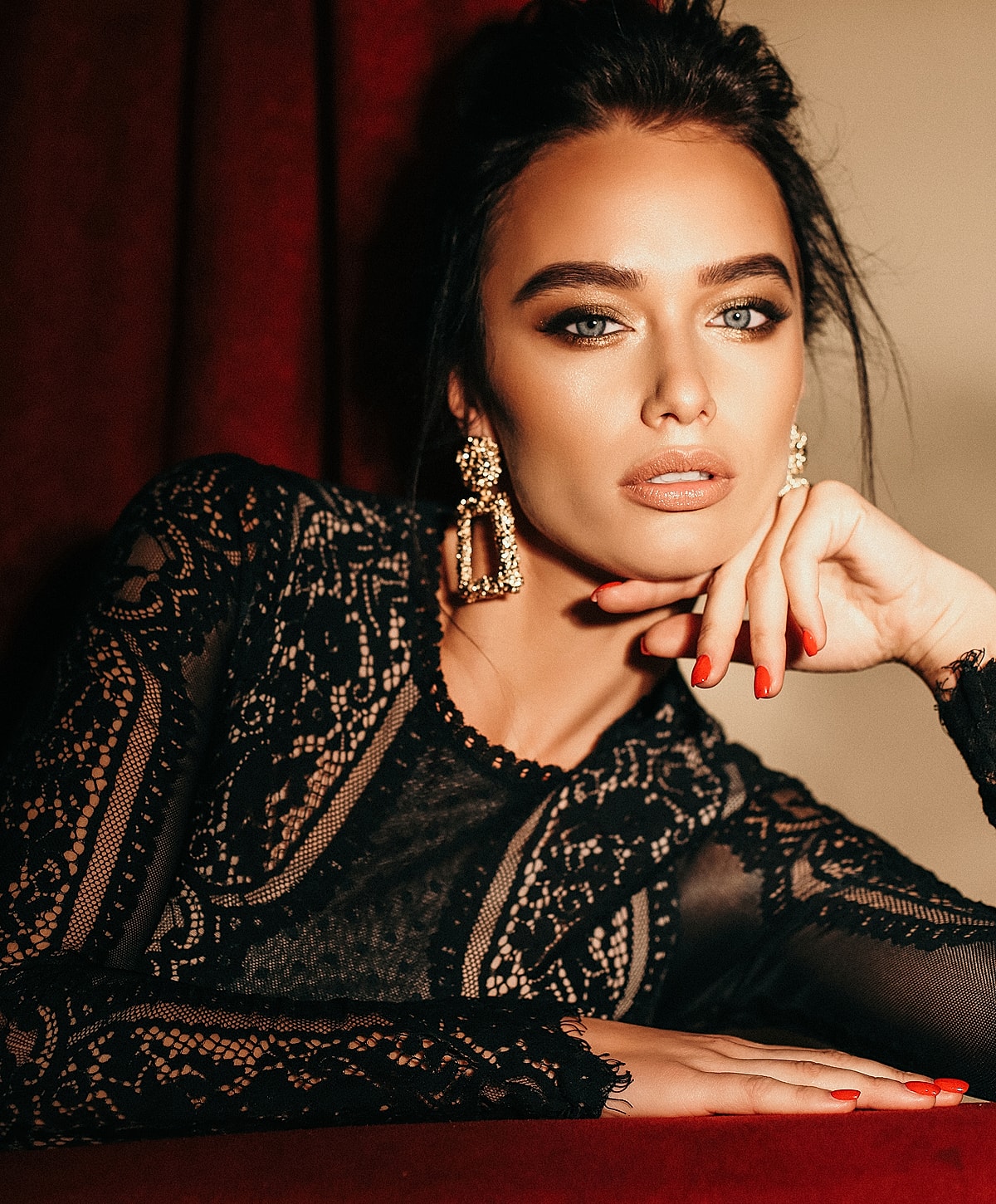 Woman in elegant black lace attire and jewelry.